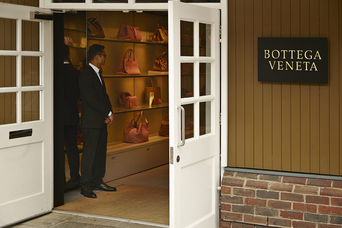 Officer in a luxury boutique doorway at Bicester Village.